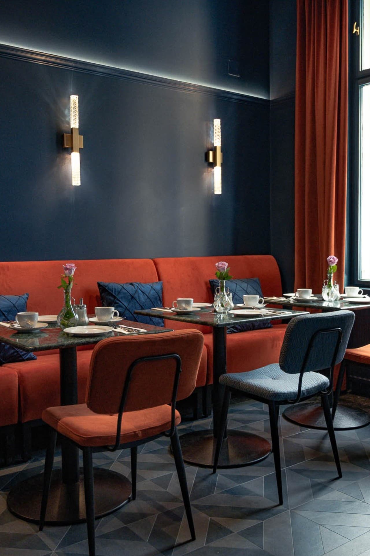 Seen is the breakfast and entry way area if the hideauts hotels Villa R, which is decoarted in the art deco Style in dark blue and orange.