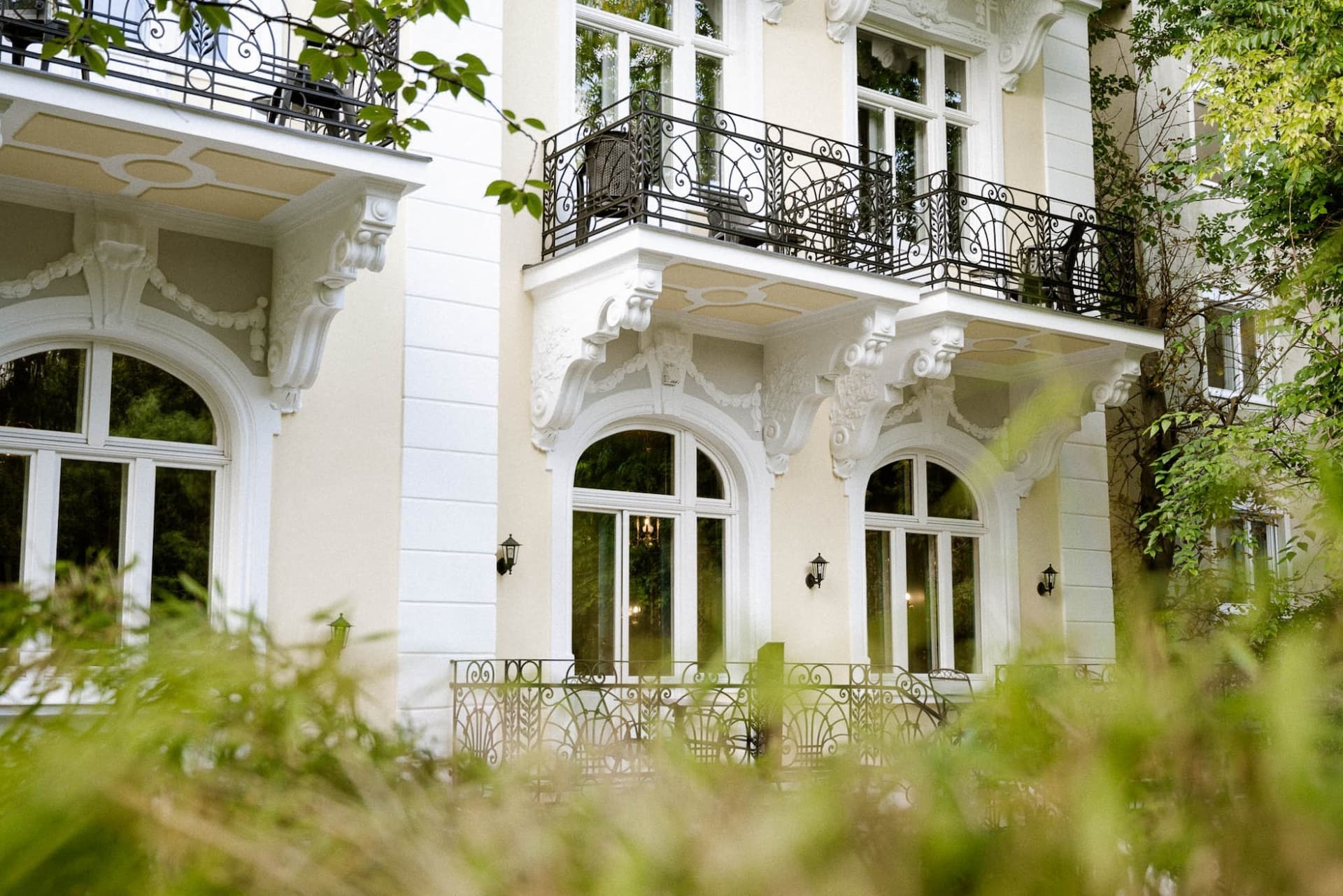 The photo shows the exterior of Villa R, with balconies and trees in the foreground.